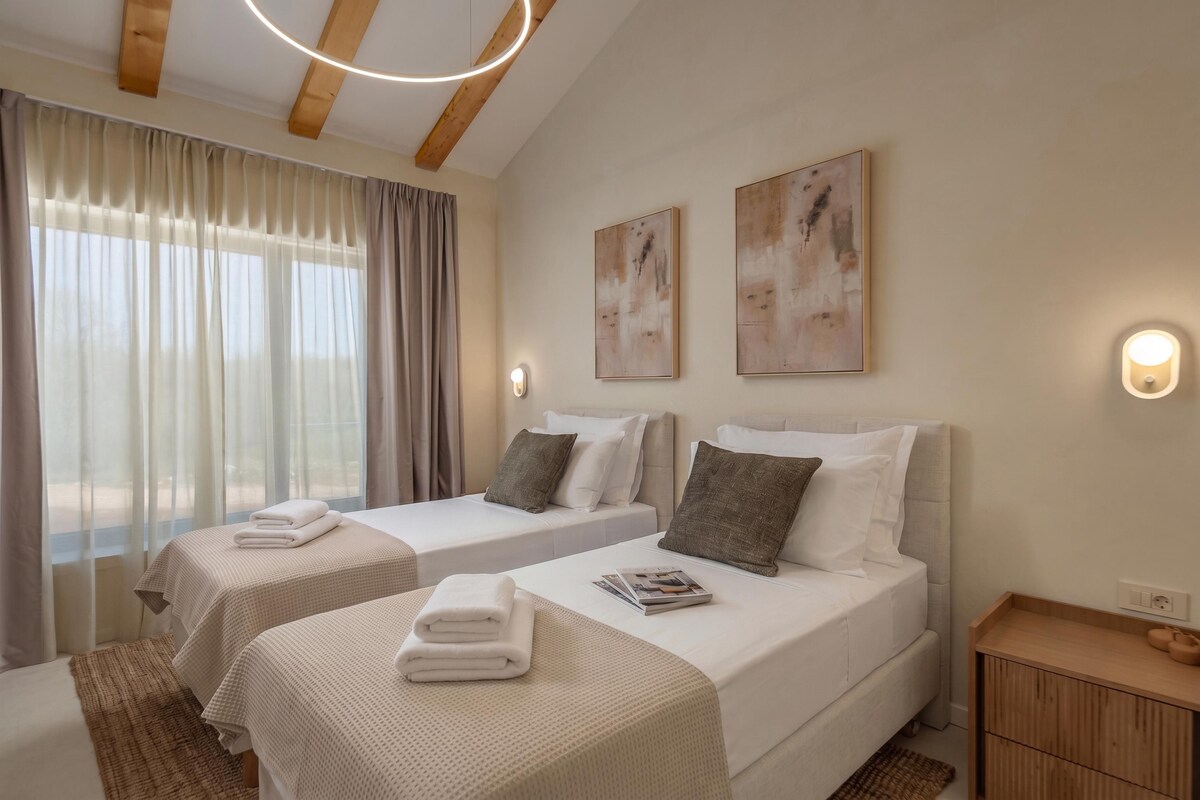 A hotel room with two beds, a wooden ceiling, a window with curtains, and wall-mounted artwork.