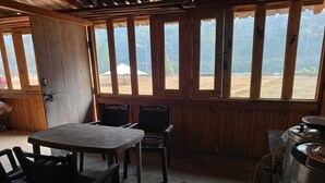Una habitación rústica de madera con una mesa, sillas, ventanas amplias y un calentador de agua.