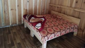 Una habitación de madera con una cama, un banco de madera y un muro de madera.