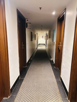 Ein Hotelkorridor mit Holztüren, einem gemusterten Teppich und einer Deckenleuchte.