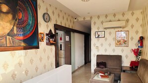 Una sala de estar con papel tapiz estampado, un sofá, una mesa de centro y un aire acondicionado instalado en la pared.