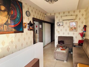 Ein Wohnzimmer mit strukturiertem Wandpapier, einem Sofa, einem Couchtisch und einer Wand-Klimaanlage.