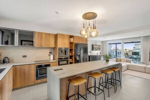 Een moderne keuken met een centraal eiland, barstoelen, inbouwapparatuur en uitzicht over de stad.