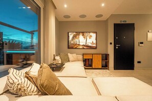 Ein modernes Hotelzimmer mit großem Fenster, einem Bett, einem Nachttisch mit Flasche, einem Gemälde, einem Schrank und einem Fluchtschild.