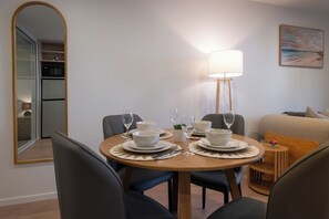 A dining area with a round table set for four, a mirror, a lamp, and a painting on the wall. - Sauna & Spa Escape | Walk to Stadium | CBD (Christchurch)