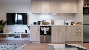 Et moderne køkken med indbyggede apparater, et fladskærms-tv og et spiseområde med et tæppe.