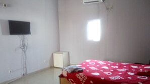 Un dormitorio con cama, televisión, aire acondicionado y ventana.