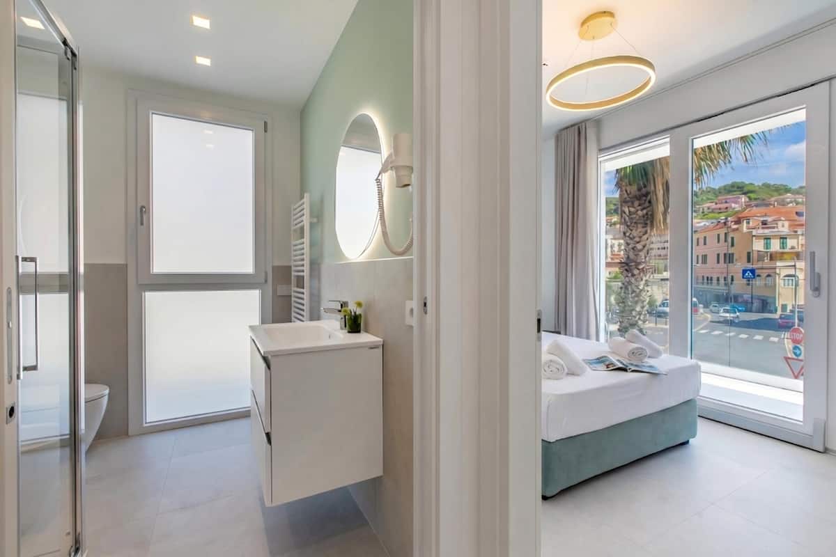 A modern hotel room with a bathroom, a bed with a view, and a large window.