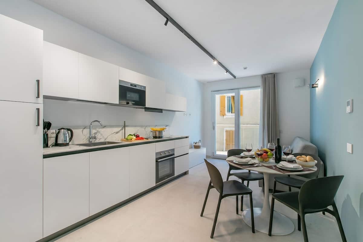 A modern kitchen with white cabinets, a microwave, and a dining area with a table set for two.