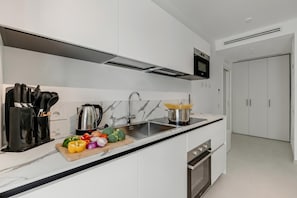 Una cocina moderna con salpicadero de mármol, electrodomésticos de acero inoxidable y encimera negra.