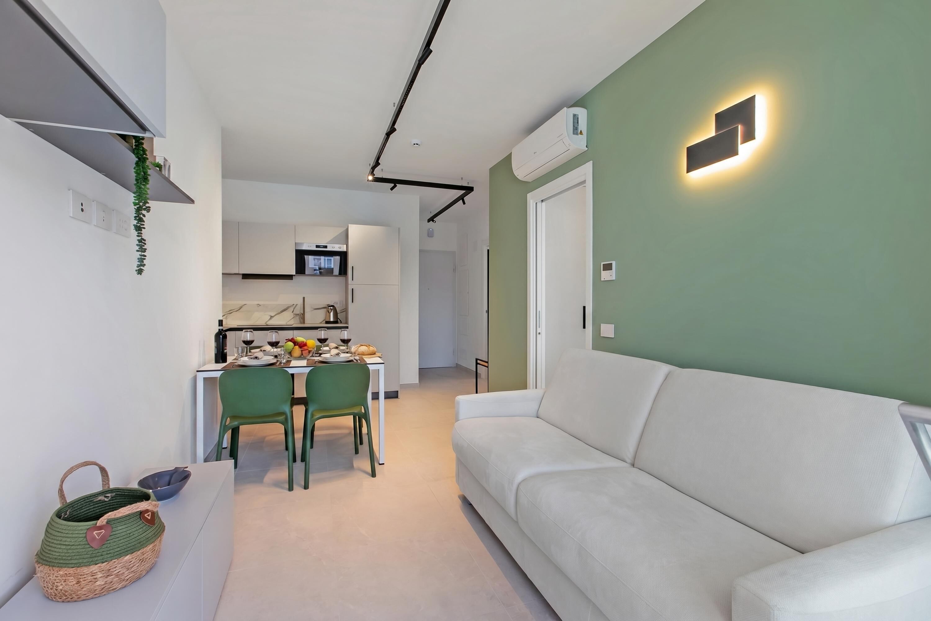 Ein moderner Wohnraum mit Sofa, Essbereich, Küche und einer Wandleuchte.