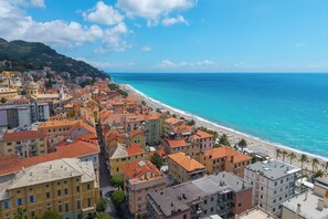 A coastal town with buildings along the beach, a clear sky, and a view of the sea.
