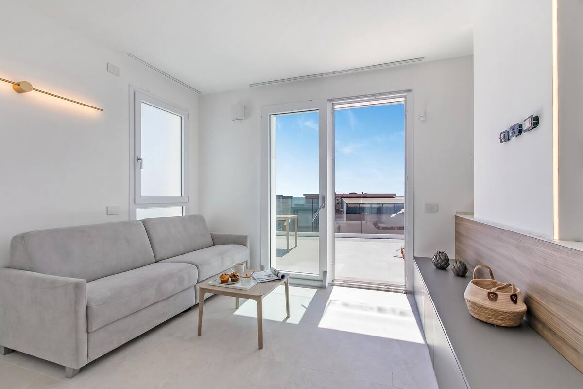 A modern living room with a sofa, a coffee table, and a sliding glass door leading to an outdoor area.