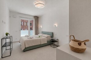 A modern bedroom with a bed, bedside table, and a woven basket on a counter.