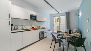 Una cuina moderna amb armaris blancs, un microones i una zona de menjador amb taula preparada per a dues persones.