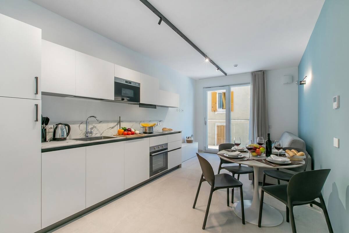 A modern kitchen with white cabinets, a microwave, and a dining area with a table set for two.