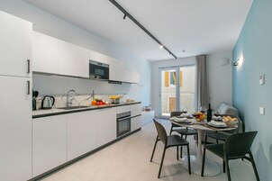 Una cucina moderna con mobili bianchi, un forno a microonde e un'area pranzo con un tavolo apparecchiato per due.