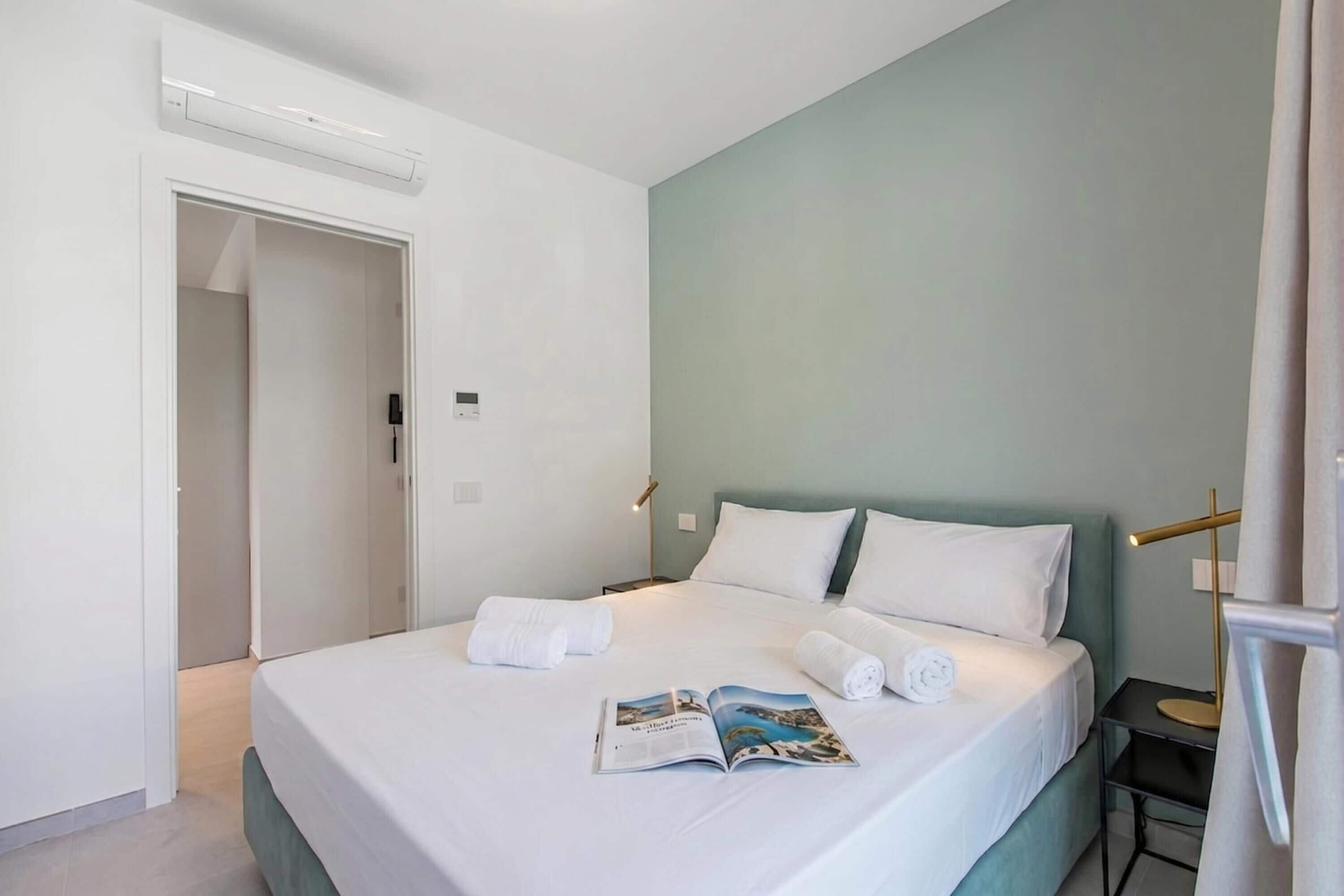 Een hotelkamer met een bed, een nachtkastje, een lamp en een tijdschrift op het bed.