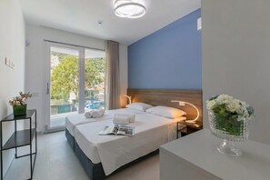 A modern hotel room with a bed, bedside table, and a view of the outdoors.