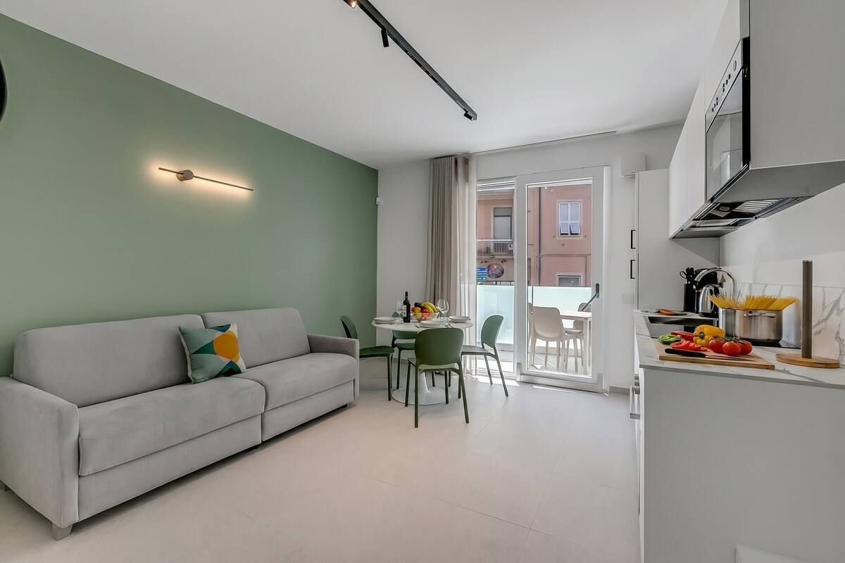 A modern living room with a sofa, a dining table, and a kitchen area with a stove and counter.
