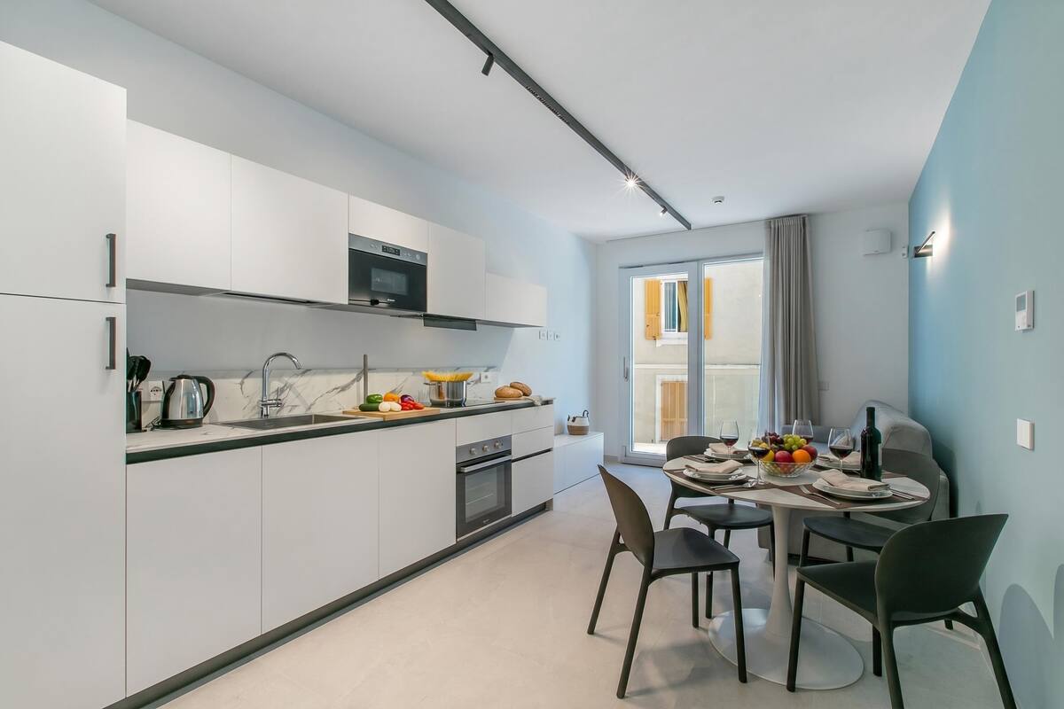 A modern kitchen with white cabinets, a microwave, and a dining area with a table set for two.