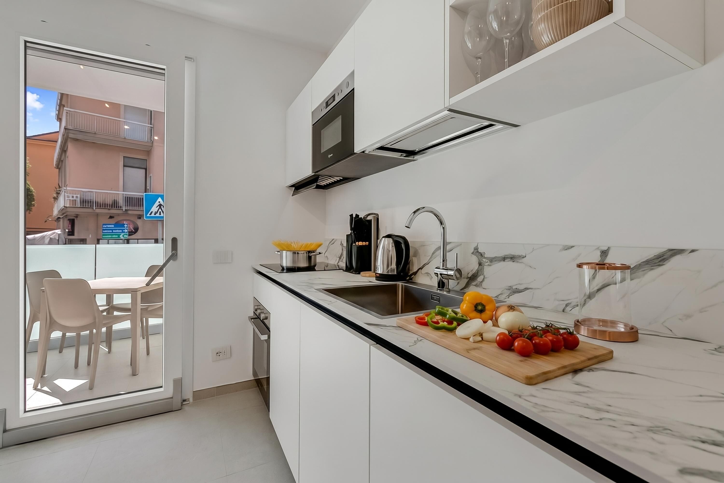 A modern kitchen with a built-in oven, a coffee maker, and a cutting board with vegetables.
