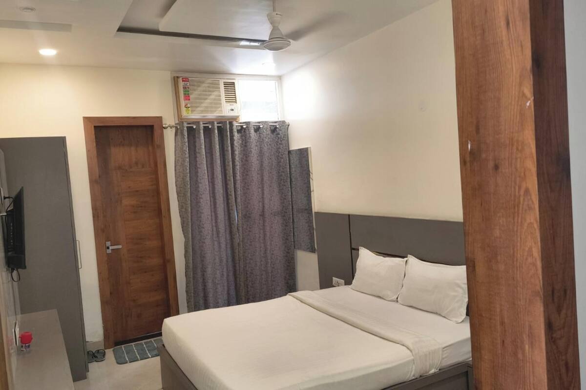 Ein Schlafzimmer mit einem Bett, einem Fernseher, einer Tür und einer Klimaanlage.