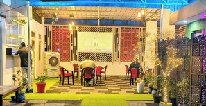 Un comedor interior con sillas rojas, piso a cuadros y una pantalla grande mostrando un evento deportivo.