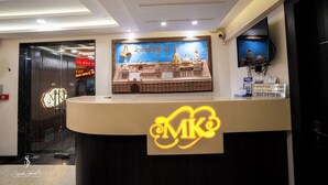 A reception desk with a large welcome sign, a wall-mounted television, and a framed picture of a building. - HOTEL M K GRAND ISHWAR TOWER (Varanasi)