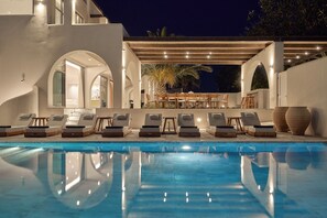 Un espace aménagé au bord de la piscine, avec des chaises longues, une pergola et une vue sur la piscine.