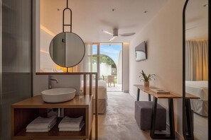 Une salle de bain moderne avec un grand miroir rond, un grand lavabo et un ventilateur de plafond.