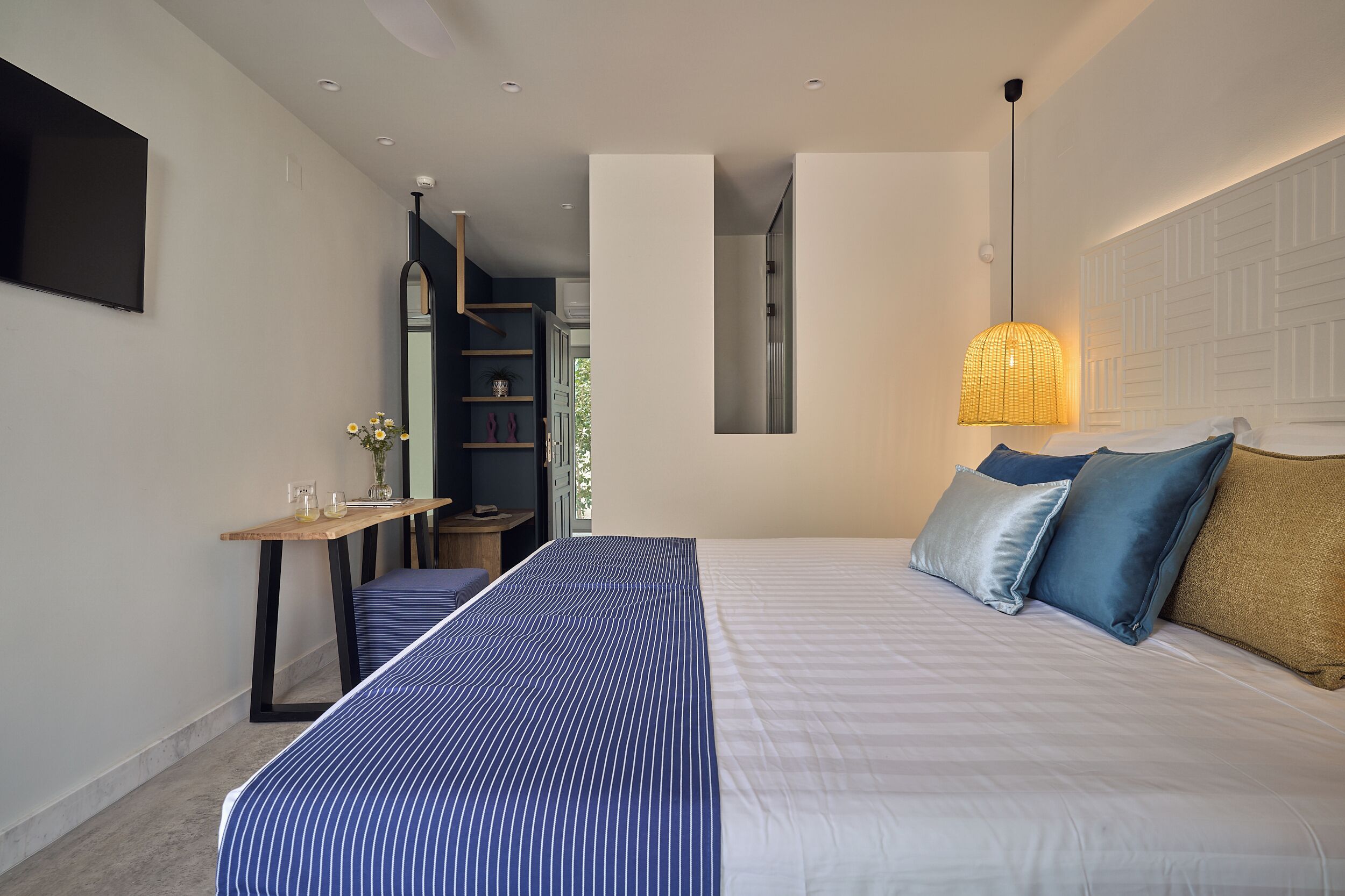 Une chambre à coucher moderne avec un lit, une table de chevet et un luminaire suspendu.