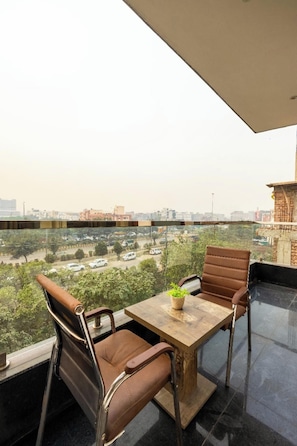 Ein Balkon mit Tisch und Stühlen, Blick auf eine Stadtlandschaft, und ein Gebäude im Hintergrund.