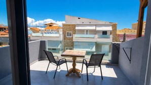A balcony with a table and chairs, a glass railing, and a view of buildings in the background. - New Horizon Sarti - Double Room with Balcony G2 (Sarti)