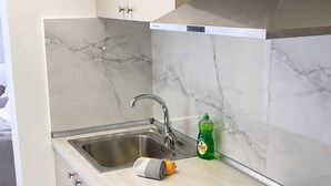 A modern kitchen with a built-in dishwasher, a stainless steel sink, and a black induction cooktop. - New Horizon Sarti - Double Room with Balcony G2 (Sarti)
