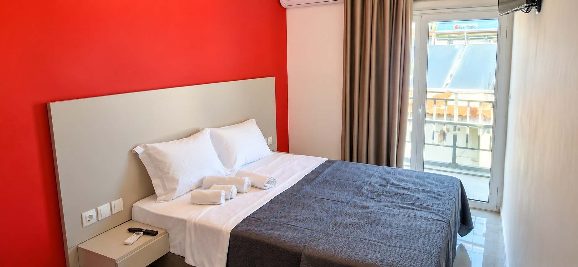 Comfortable Double Bedroom with Red Accent Wall and Balcony Access