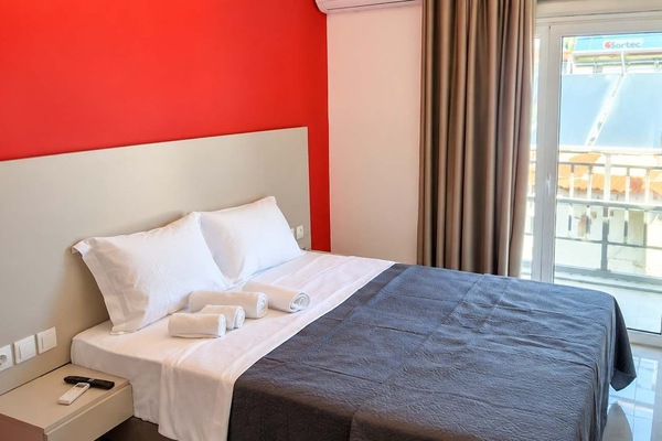 Comfortable Double Bedroom with Red Accent Wall and Balcony Access