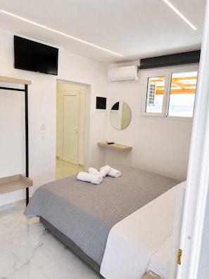 A modern bedroom with a bed, a TV, a mirror, and a window. - New Horizon Sarti - Ground Floor Double A1 (Sarti)