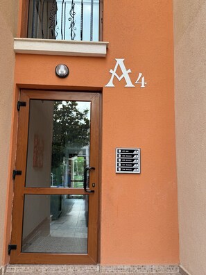 A building entrance with a glass door, a metal gate, and a wall-mounted sign indicating floor numbers and room counts. - Cozy Beachfront Apt with Pool @ Prestige Fort Beach⁠ (Sveti Vlas)