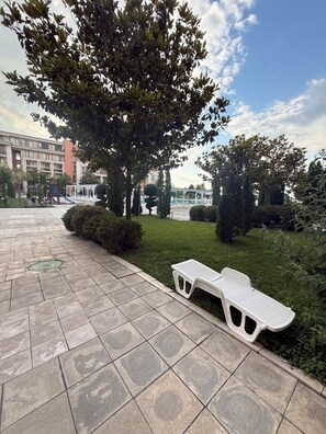 A paved walkway with a bench, a playground, and a large tree. - Cozy Beachfront Apt with Pool @ Prestige Fort Beach⁠ (Sveti Vlas)