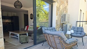 A modern living area with a sliding glass door leading to a balcony, a dining table, and two cushioned chairs. - 3-room apartment with a view of the Citadel, a terrace, and a free garage, just 500 meters from the sea! (Calvi)