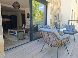 A modern living area with a sliding glass door leading to a balcony, a dining table, and two cushioned chairs. - 3-room apartment with a view of the Citadel, a terrace, and a free garage, just 500 meters from the sea! (Calvi)