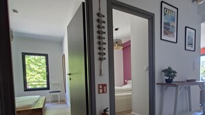 A modern interior with a wooden floor, a bed, a small table, and a fire extinguisher. - 3-room apartment with a view of the Citadel, a terrace, and a free garage, just 500 meters from the sea! (Calvi)