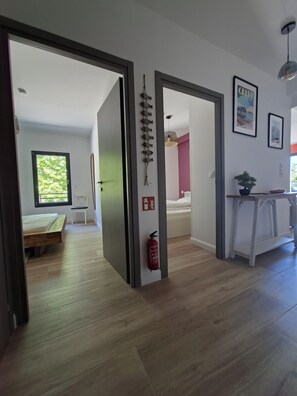 A modern interior with a wooden floor, a bed, a small table, and a fire extinguisher. - 3-room apartment with a view of the Citadel, a terrace, and a free garage, just 500 meters from the sea! (Calvi)