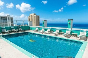 A rooftop pool with lounge chairs and a view of the ocean and city skyline. - 2 Studios with Access to Rooftop BBQ & Pool | 3-Min Walk to Beach (Honolulu)