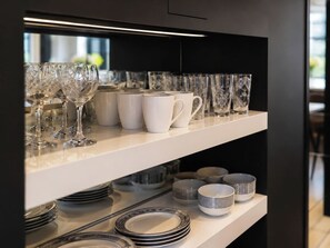 Eine Küche mit weißen Regalen, auf denen verschiedenes Glas und Geschirr steht.