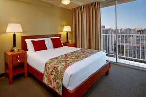 Ein Hotelzimmer mit einem großen Bett, zwei Nachttischen, einem Fenster mit Vorhängen und Blick auf die Stadt.