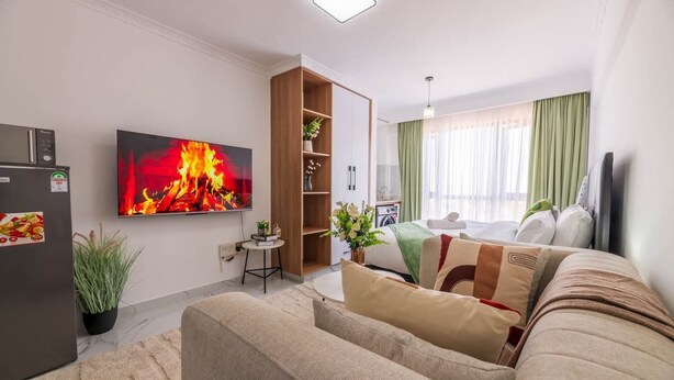 Een moderne woonkamer met een flatscreen televisie, een bank, een klein tafeltje en een houten kast.