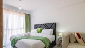 Een moderne slaapkamer met een bed, nachtkastje, lamp en een sofa.