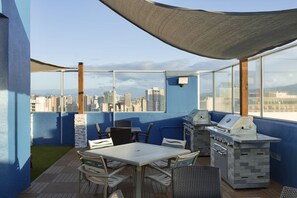 Eine Terrasse im Freien mit Grill, Sitzgelegenheiten und Blick auf die Stadt.